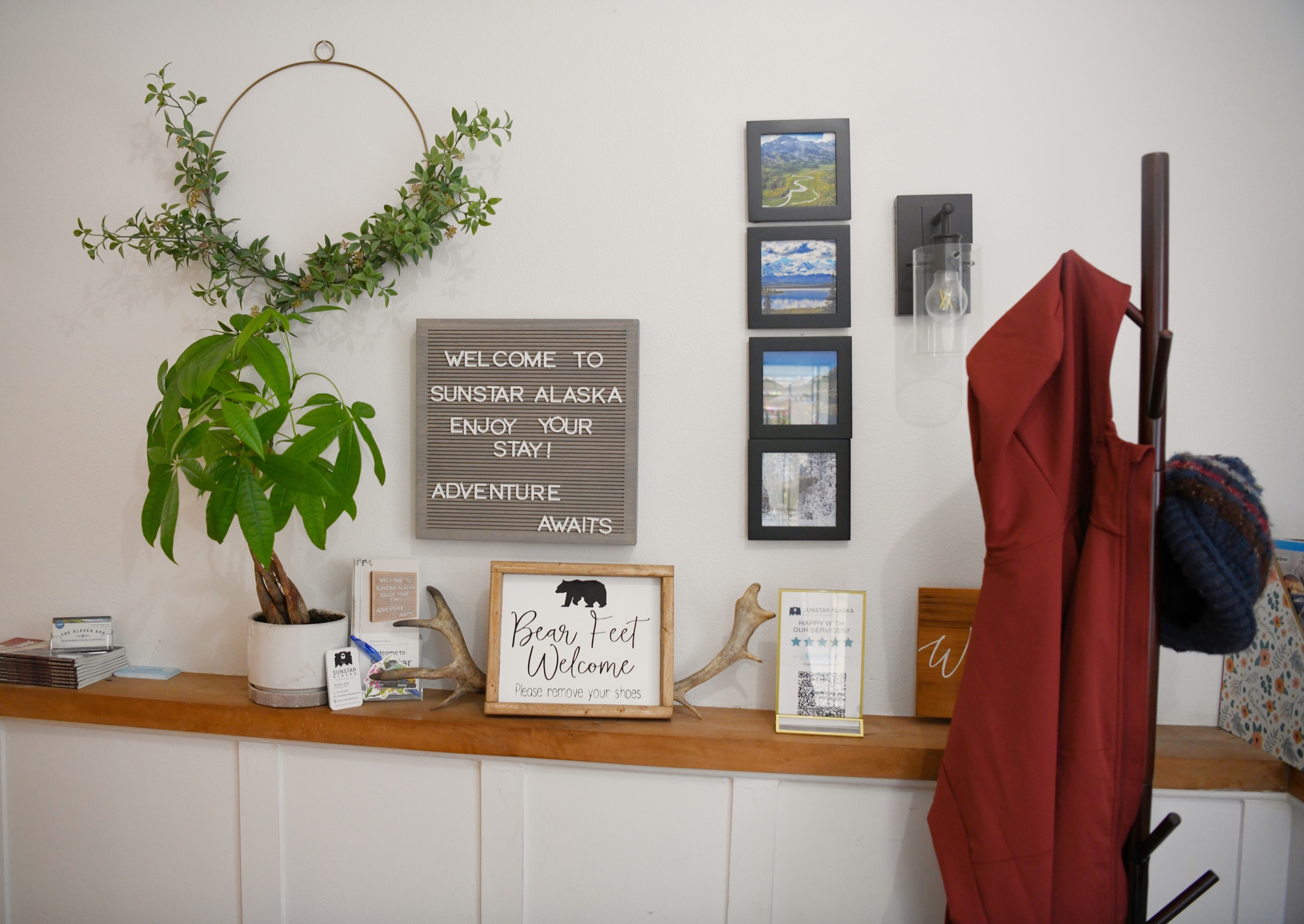 A welcome letter board, framed Alaska photos and a Bear Feet Welcome sign above an entry shelf